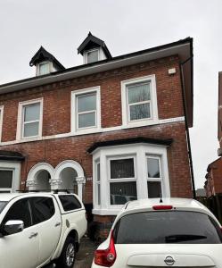 deux voitures garées devant une maison en briques dans l'établissement Cheerful newly refurbed 5 bed!, à Derby