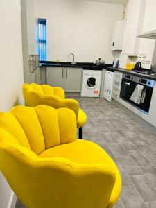 a kitchen with a yellow chair in a kitchen at Cheerful newly refurbed 5 bed! in Derby