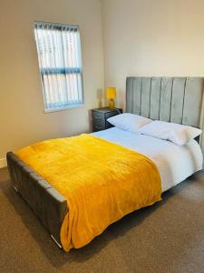 a bedroom with a large bed with a yellow blanket at Cheerful newly refurbed 5 bed! in Derby