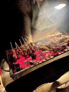a grill with meat on skewers in an oven at Desert Moments Glamping - full privacy in Muntarib