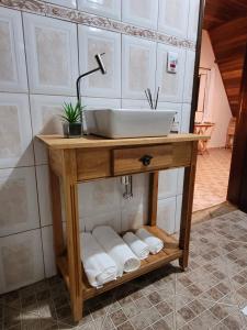 uma casa de banho com um lavatório e uma prateleira com toalhas em Villa das Palmeiras Chalés & Camping em São Bento do Sapucaí