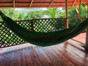 a green hammock on a porch with a deck at PALUM Prívate Room share bathroom in Palomino
