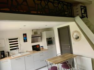 a kitchen with white cabinets and a table with chairs at Studio à la campagne in Montcornet