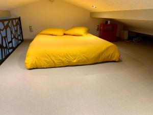a bed with yellow sheets and pillows in a room at Studio à la campagne in Montcornet