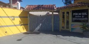 a yellow building with a gate with a sign on it at Suites por do Sol in Búzios