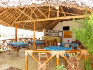 a restaurant with tables and chairs under a thatched roof at Serenity 2 - Jambiani in Jambiani