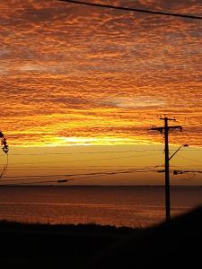 a sunset over the ocean with a telephone pole at Auberge Vue d'la Dune - Dune View Inn in Bouctouche