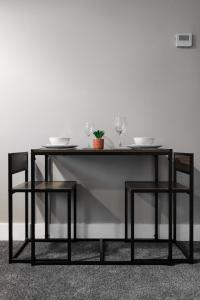 a dining table with two glasses and two chairs at City Centre Studio 1 with Kitchenette, Free Wifi and Smart TV with Netflix by Yoko Property in Middlesbrough