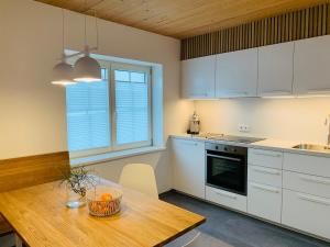 eine Küche mit weißen Schränken und einem Holztisch in der Unterkunft Dorf(er)leben Ferienwohnung im Kleinwalsertal in Mittelberg