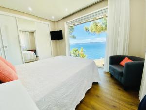 a bedroom with a white bed and a large window at Casa A Colina in Porto do Son