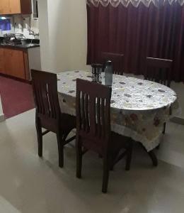 a dining room table with two chairs and a table with a tablecloth at Global Mansion Service Apartment in Bangalore