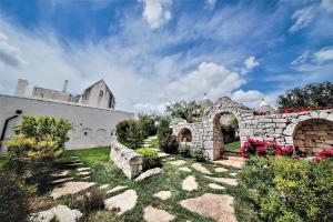 洛科羅通的住宿－Trulli Arco Antico，庭院里一座石头建筑,花朵花