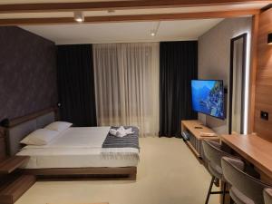 um quarto de hotel com uma cama e uma televisão de ecrã plano em Woodside apartments Kopaonik em Kopaonik