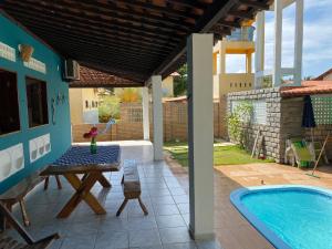 a patio with a table and a swimming pool at Japaraiso I Casa Azul - Próxima ao Mar in Japaratinga
