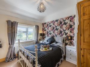 a bedroom with a bed with a floral accent wall at Flyby Cottage in Symonds Yat