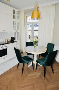 a kitchen with a table and green chairs at GOLD APARTMENT Piotrkowska 37 in Łódź
