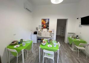 a room with two green tables and a kitchen at La Maison in Acquaviva delle Fonti
