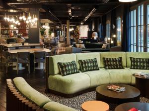 a living room with a couch and tables and chairs at TRIBE Hôtel Le Touquet in Le Touquet-Paris-Plage