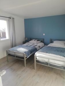 two beds in a bedroom with blue walls at Jolie maison à 200 m des plages du débarquement in Saint-Aubin-sur-Mer