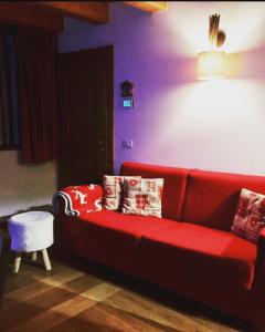 a living room with a red couch with pillows at Casa Romeo in San Vito di Cadore