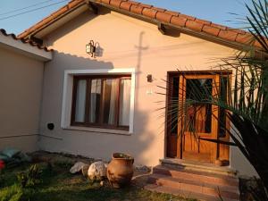 Casa blanca pequeña con puerta de madera en Canela House en Huerta Grande