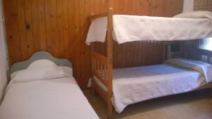 Ce lit se trouve dans un dortoir doté de 2 lits superposés et de murs en bois. dans l'établissement Canela House, à Huerta Grande