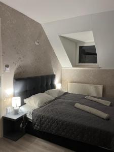 1 dormitorio con 1 cama grande y cabecero gris en Jager Guesthouse, en Sopron