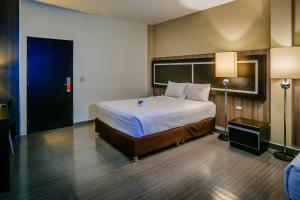 a hotel room with a large bed and a lamp at Rado Hotel - Santa María in Trujillo