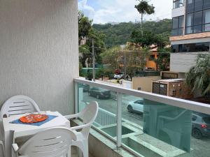 una mesa y sillas en un balcón con vistas a la calle en Residencial Amanda, en Bombinhas