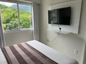 a bedroom with a bed with a tv and a window at RioStay Residence, Riocentro in Rio de Janeiro