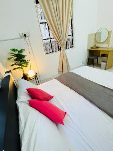 - une chambre avec un lit doté de 2 oreillers rouges dans l'établissement QV Residence Langkawi - Jacuzzi, BBQ, & Steamboat, à Kuah
