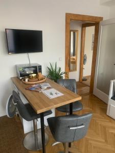 Zimmer mit einem Holztisch mit Stühlen und einem TV in der Unterkunft Apartment Anenská by Charles Bridge in Prag