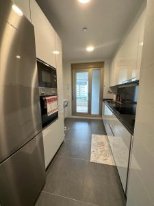 a large kitchen with a stainless steel refrigerator at A estrenar amplio con piscina y parking in Getxo