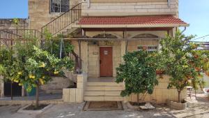 a house with a wooden door and two trees at Issa's House in Bayt Sāḩūr