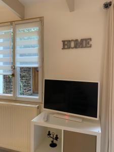 TV de pantalla plana sobre una mesa blanca en Aux Vieilles Murailles • Charmante maison & cour, en Morlaix