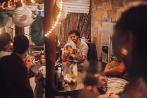 a man playing a guitar in a room with people at João Jungle in Açafora