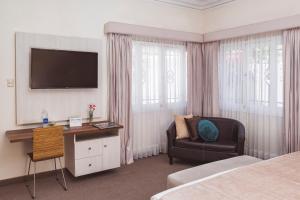 a hotel room with a bed and a chair and a television at Hostal Lirium in Arequipa