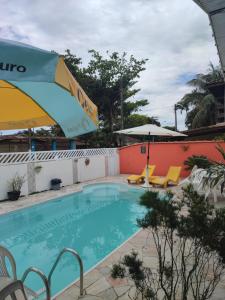 una piscina con una sombrilla y 2 sillas y una sombrilla en Jdu Hostel e Bar, en Bertioga