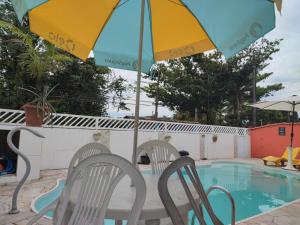 einen Pool mit 2 Stühlen und einem Sonnenschirm in der Unterkunft Jdu Hostel e Bar in Bertioga