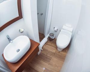 La salle de bains est pourvue d'un lavabo blanc et de toilettes. dans l'établissement Hostal Lirium, à Arequipa