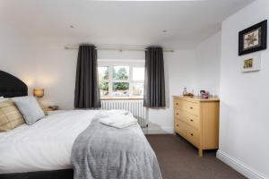 a bedroom with a bed and a dresser and a window at Forge Cottage in Winchcombe