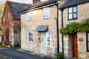 a stone house with a white door on a street at Forge Cottage in Winchcombe