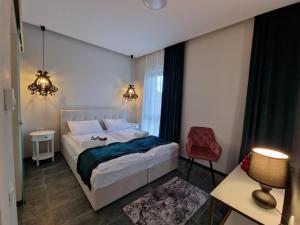 um quarto com uma cama e uma cadeira vermelha em Art's Luxury Boutique Hotel em Oradea