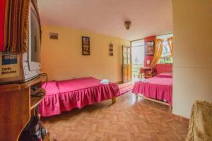 Secret Valley House Cusco في أولانتايتامبو: سريرين في غرفة ذات أغطية وردية