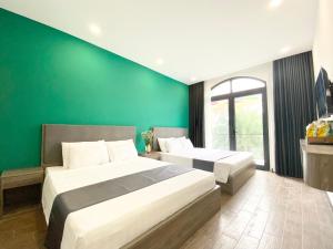 2 łóżka w pokoju z zieloną ścianą w obiekcie Elpis Hotel Phu Quoc w Duong Dong