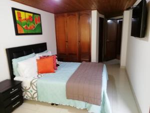 um quarto com uma cama e uma televisão de ecrã plano em Habitaciones en Edificio Ginebra Manizales em La Linda