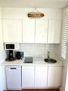 una cucina con armadi bianchi e lavandino di KARIBEKO : Exceptionnel & Rare : Plage , Piscine, WiFi privé a Saint-François