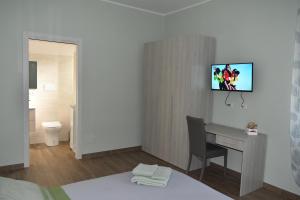 a hotel room with a desk and a tv on the wall at Armonia family B&b in Crotone