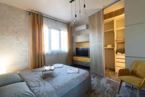 a bedroom with a bed and a chair and a television at Unique Central 1 Bedroom Flat in Sofia
