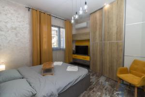 a bedroom with a bed and a chair and a television at Unique Central 1 Bedroom Flat in Sofia